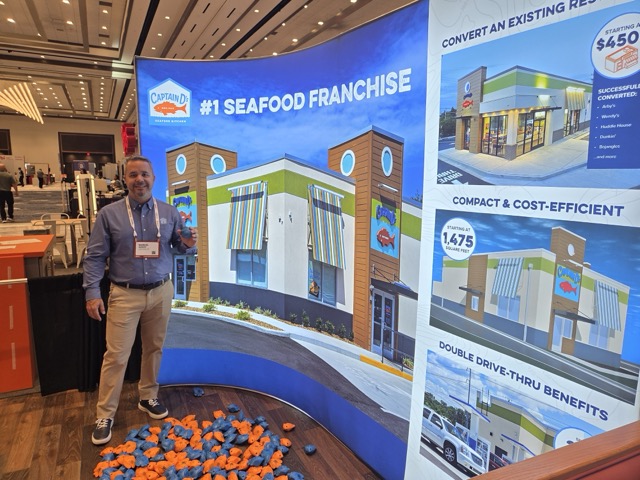 Wall display for Captain D's #1 Seafood Franchise, with a stack of squish fish on the floor and a person holding a squish fish.